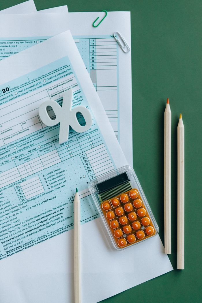 Offerings Flat lay of tax documents, calculator, and pencils on green surface.
