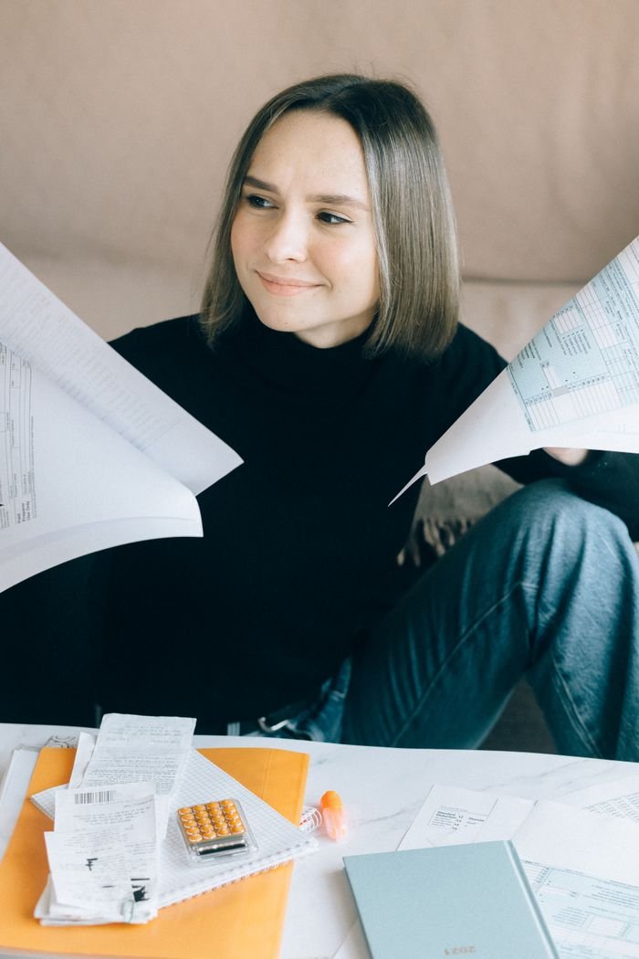 Offerings Young woman sorting tax documents and papers at home office desk.